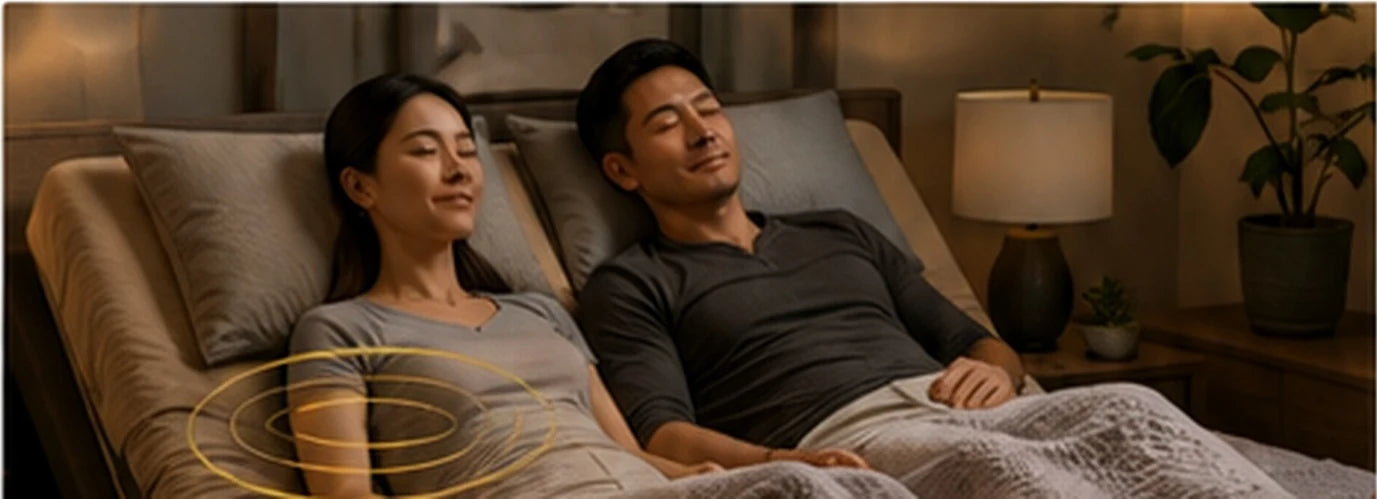 Fit Asian couple relaxing together while using the massage feature on a luxury adjustable bed